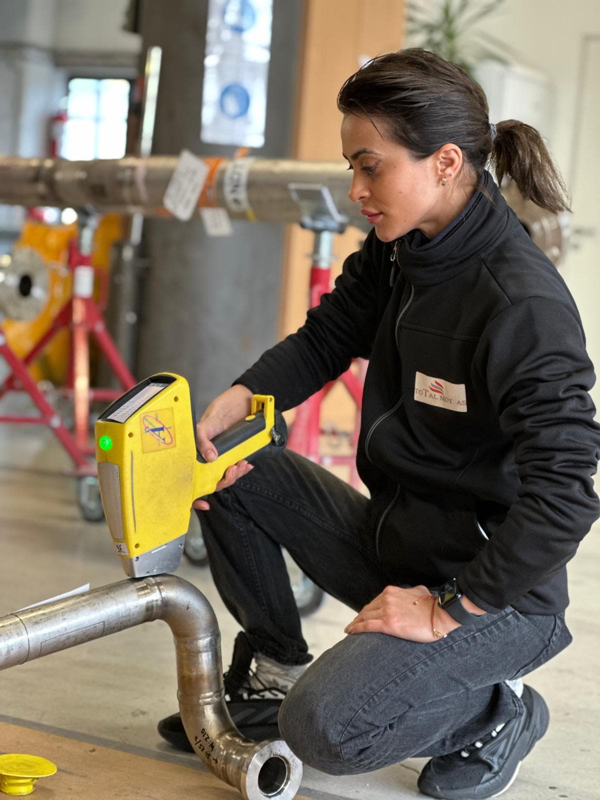 Inspector examining a metal pipe with a positive material identification tool