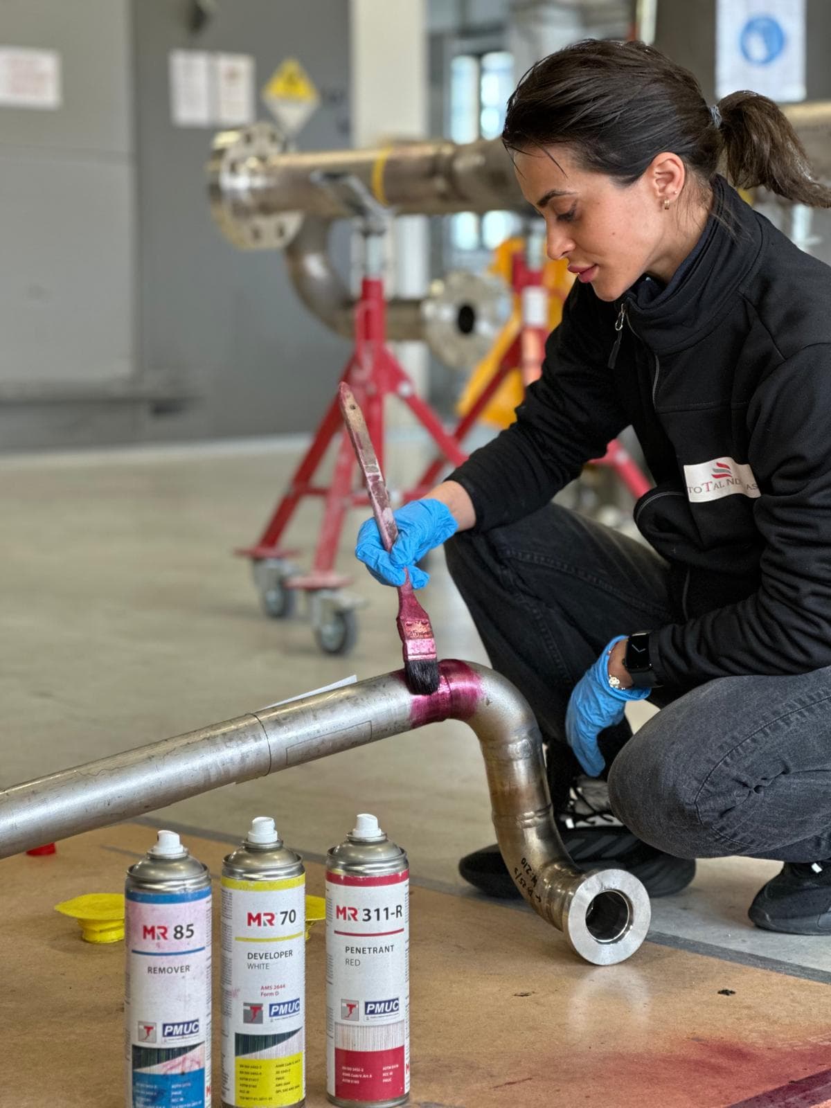 NDT inspector examining a metal pipe with liquid penetrant
