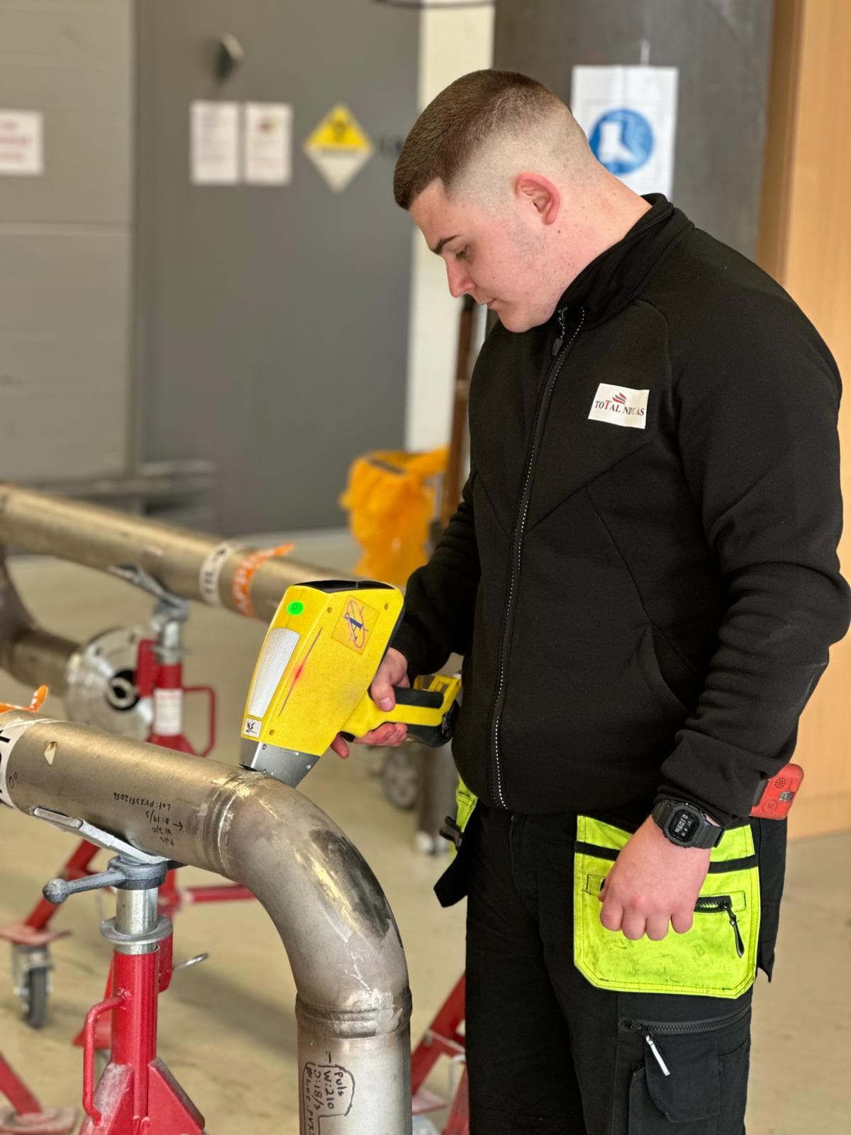 Inspector examining a metal pipe with a positive material identification tool